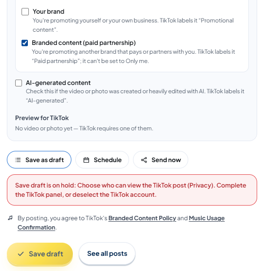 Bottom of the TikTok panel: "Your brand" unticked and "Branded content (paid partnership)" ticked, "AI-generated content", the preview "No video or photo yet — TikTok requires one of them."; below that, the Save as draft option (selected), a red box "Save draft is on hold: Choose who can view the TikTok post (Privacy). Complete the TikTok panel, or deselect the TikTok account.", the sentence "By posting, you agree to TikTok's Branded Content Policy and Music Usage Confirmation.", and the Save draft button.