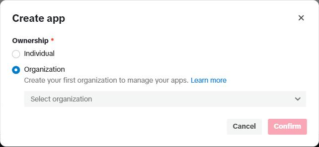 Jendela "Create app": bagian "Ownership" dengan pilihan Individual dan Organization (terpilih), kalimat "Create your first organization to manage your apps. Learn more", kotak "Select organization", serta tombol Cancel dan Confirm (masih pudar).